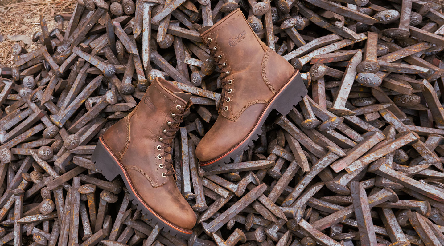 A pair of Classic 2.0 unlined steel toe loggers displayed on a pile of rail spikes.